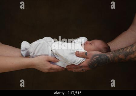 Bébé nouveau-né tenu en toute sécurité par ses parents solides mains sécurisées. Banque D'Images