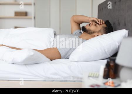 Vue latérale de l'homme arabe malade couché au lit à la maison Banque D'Images