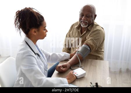 Femme noire médecin vérifiant la pression de mesure sur la main du patient Banque D'Images