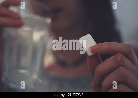 Femme mangeant du sucre et de l'eau potable pour traiter un sucre bas (Hypo) Banque D'Images