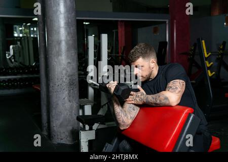 Homme tatoué faisant de l'exercice avec les petits de la main dans la salle de gym. Mode de vie sain, concept d'entraînement Banque D'Images