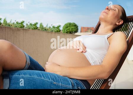 Gros plan de la femme enceinte se reposer dans une chaise longue Banque D'Images