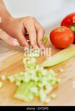 Le dicing est un bel art. gros plan d'une femme hacher un concombre frais. Banque D'Images