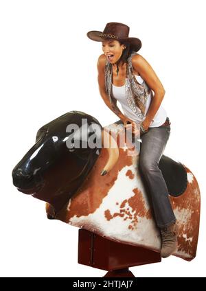 Ouah. Photo studio d'une belle jeune femme à cheval sur un taureau mécanique sur fond blanc. Banque D'Images