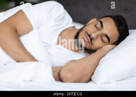 Portrait d'un jeune homme beau du Moyen-Orient dormant au lit à la maison Banque D'Images