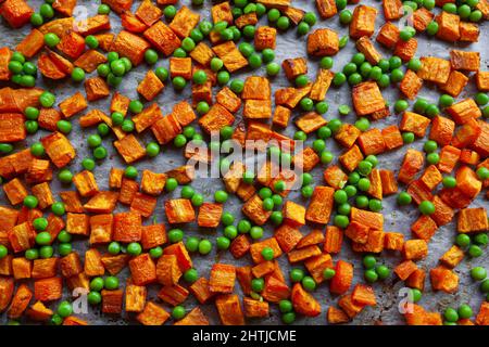 Carottes grillées au four, patates douces et petits pois verts sur papier parchemin, coupés en cubes Banque D'Images