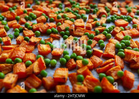 Carottes grillées au four, patates douces et petits pois verts sur papier parchemin, coupés en cubes Banque D'Images