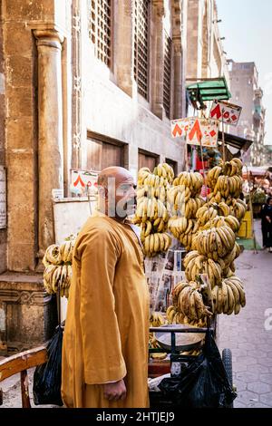 Le Caire, Egypte - 11 janvier 2022: Vendeur local en tenue traditionnelle à la stalle vendant des bananes dans la rue du Grand Bazar Banque D'Images