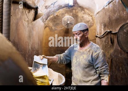 Le Caire, Egypte - 11 janvier 2022: Vendeur debout dans une petite cabine avec des murs de merde tout en montrant des épices de terre sur la pelle Banque D'Images
