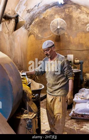 Le Caire, Egypte - 11 janvier 2022: Vendeur debout dans une petite cabine avec des murs de merde tout en montrant des épices de terre sur la pelle Banque D'Images
