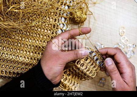 De dessus de récolte anonyme personne talentueuse crotcheting courrier de chaîne avec anneaux en aluminium doré tire tout en travaillant dans l'atelier léger Banque D'Images