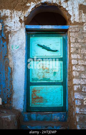 Porte peinte lumineuse de la maison négligée avec porte voûtée et mur de merde rugueux situé sur la rue de la ville en Egypte Banque D'Images