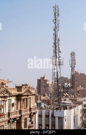 Bâtiments résidentiels élevés situés dans la rue près de la tour de transmission avec des satellites contre le ciel sans nuages en Égypte Banque D'Images