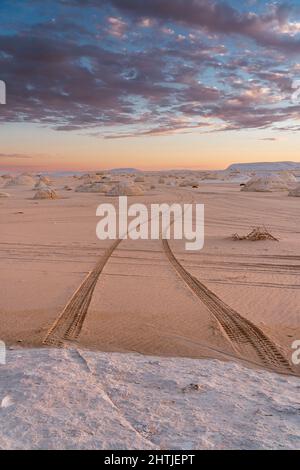 Pistes de voiture sur un sol sablonneux dans un désert blanc protégé avec des formations rocheuses craies situées contre le ciel nuageux en Egypte Banque D'Images