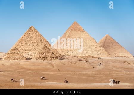 Touriste dans les anciennes grandes pyramides égyptiennes situé sur un terrain sablonneux à Gizeh contre un ciel bleu sans nuages le jour d'été ensoleillé au Caire Banque D'Images