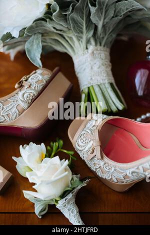 De dessus doux boutons blancs et chaussures de mariée décorées placées sur une table en bois poli Banque D'Images