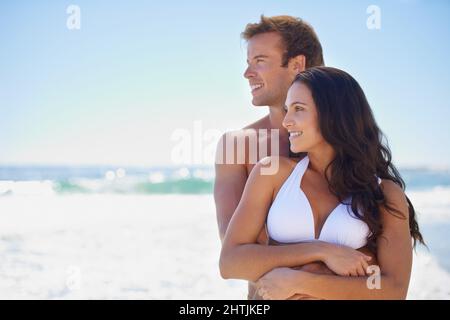 Admirer la beauté de la vue ensemble. Un couple heureux se tenant les uns les autres sur la plage et donnant sur l'océan. Banque D'Images