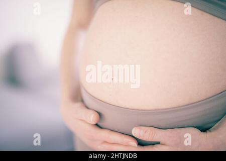 Femme enceinte ventre. Concept de grossesse. Ventre de la femme enceinte en gros plan. Détail de la femme enceinte détendue à la maison. Banque D'Images