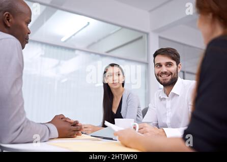 Tous les sourires de la réunion du matin. Un groupe de collègues assis dans un bureau et ayant une réunion. Banque D'Images