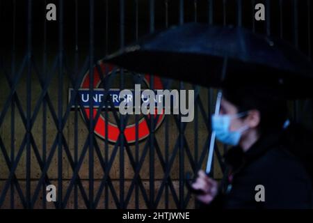 Une femme tenant un parapluie passe devant la station de métro de Westminster qui est dotée de barres métalliques à l'entrée, toutes les lignes de métro de Londres étant suspendues pendant une grève par des membres du RMT. Date de la photo: Mardi 1 mars 2022. Banque D'Images