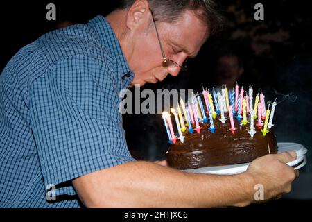 l'homme souffle ses bougies d'anniversaire à l'anniversaire Banque D'Images