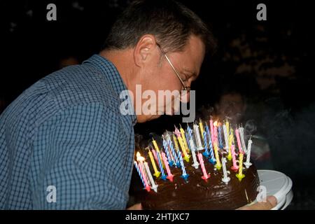 l'homme souffle ses bougies d'anniversaire à l'anniversaire Banque D'Images