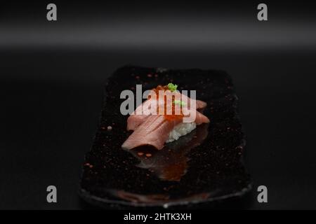 Le thon Otoro est la partie la plus hâtives du thon. Délicieux deux nigiris de thon japonais servis sur du riz blanc avec du wasabi et du caviar. Arrière-plan noir. Banque D'Images