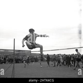 1960s, historique, sports scolaires, un adolescent faisant le saut à la hausse, en utilisant sa propre technique, Écosse, Royaume-Uni. Banque D'Images