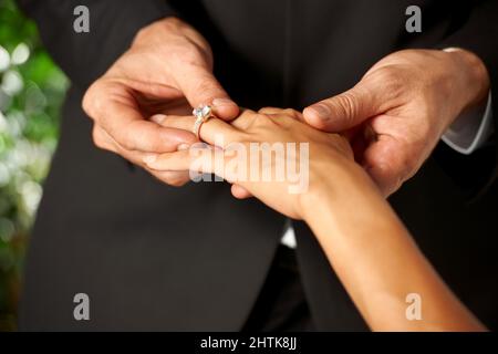 Ils se promettre leur amour. Vue rognée d'un marié glissant un anneau sur son doigt de mariée. Banque D'Images