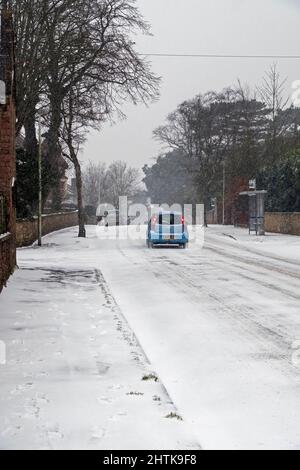 Une voiture traverse la neige qui tombe sur une route déserte à Weston-super-Mare, au Royaume-Uni, le 1 mars 2018, lors de la tempête surnommée « la Bête de l'est ». Banque D'Images