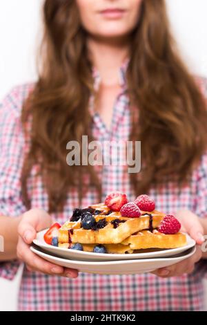 Gros plan d'une fille tenant des gaufres avec des fruits et du sirop dans une assiette blanche Banque D'Images