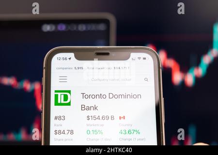 Le cours de l'action de la Banque Toronto Dominion sur l'écran du téléphone cellulaire dans les mains de l'évolution de la bourse avec analyse graphique de chandelier de négociation, février 2022, San Francisco, États-Unis Banque D'Images