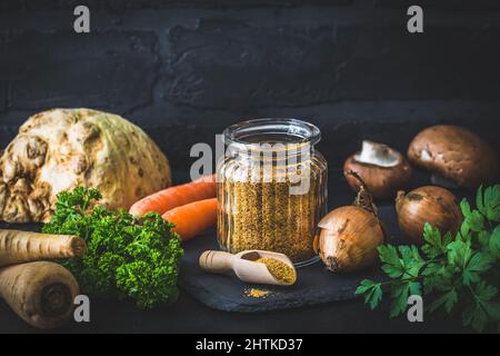 Bouillon de légumes maison en poudre, bouillon de légumes bio, avec légumes crus sur fond noir, espace de copie Banque D'Images