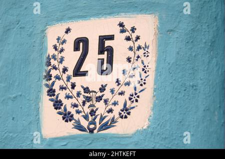 Rue numéro 25 dans une tuile avec des ornements dans un mur de peinture bleu Banque D'Images