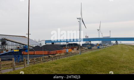 01 mars 2022, Schleswig-Holstein, Brunsbüttel : des éoliennes se trouvent devant une installation de stockage de charbon sur la digue d'Elbe, au port de Brunsbüttel. La zone est en discussion en tant que site pour un nouveau terminal de GNL (gaz naturel liquéfié). Photo: Frank Molter/dpa Banque D'Images