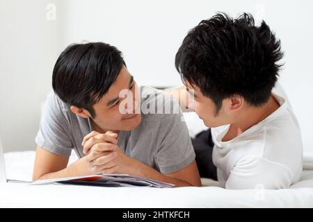 Vivre et aimer ensemble. Mignon jeune gay asiatique couple souriant tout en se relaxant à la maison ensemble. Banque D'Images