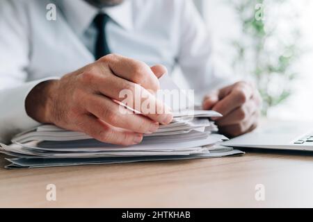 Le responsable des RH lisant les CV des candidats des employés est empilé sur le bureau, en se concentrant de manière sélective Banque D'Images
