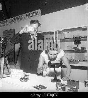 Historique de la caméra. Un homme avec un Jules Richard Paris Verascope le tient à un salon. L'appareil photo a pris deux photos de la scène et les diapositives ont pu être visualisées dans des visualiseurs d'images dédiés pour découvrir la profondeur et l'effet de la photographie à deux lentilles. La femme montre un tel spectateur qui est visible sur la table. Suède 1951 Kristoffersson réf. BD95-12 Banque D'Images