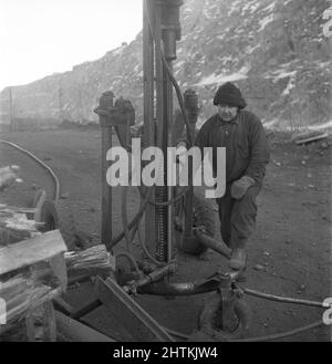 Kiruna Suède en 1950s. La mine à ciel ouvert et les ouvriers forant des trous pour y mettre des explosifs. Le semoir est alimenté par de l'air comprimé et le bruit aurait été très élevé mais l'homme qui travaille avec lui semble ne pas remarquer le son, même sans porter de protection auditive. Il a peut-être déjà eu une telle mauvaise audition que le problème de la haute noice n'est pas un problème. Suède 1954 Kristoffersson BP22-9 Banque D'Images