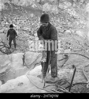 Kiruna Suède en 1950s. La mine à ciel ouvert et les ouvriers forant des trous pour y mettre des explosifs. Le semoir est alimenté par de l'air comprimé et le bruit aurait été très élevé mais l'homme qui travaille avec lui semble ne pas remarquer le son, même sans porter de protection auditive. Il a peut-être déjà eu une telle mauvaise audition que le problème de la haute noice n'est pas un problème. Suède 1954 Kristoffersson BP23-5 Banque D'Images