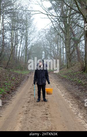 Un portrait d'un jeune barbu avec un picker de litière et un seau prêt à faire un ramassage de litière et nettoyer la campagne. Litières, déchets, envi Banque D'Images