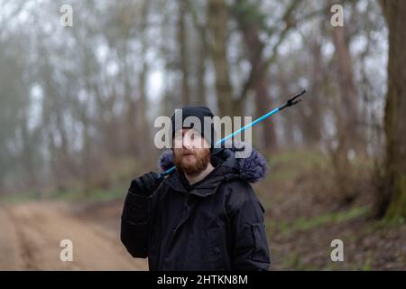 Un portrait d'un jeune barbu avec un picker de litière et un seau prêt à faire un ramassage de litière et nettoyer la campagne. Litières, déchets, envi Banque D'Images