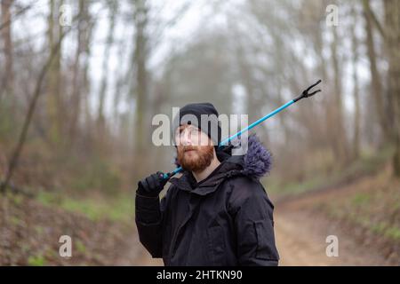 Un portrait d'un jeune barbu avec un picker de litière et un seau prêt à faire un ramassage de litière et nettoyer la campagne. Litières, déchets, envi Banque D'Images