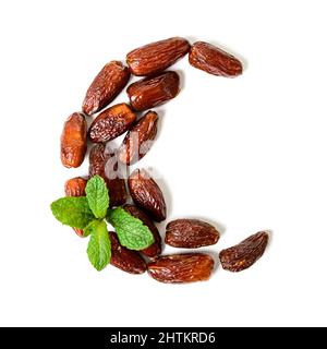 Dattes séchées sous forme d'un mois avec des feuilles de menthe sur fond blanc. Le concept du mois islamique du Ramadan. Banque D'Images