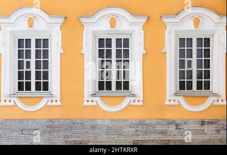 Détails de l'architecture classique, fenêtres avec cadres blancs et décoration dans le mur de pierre jaune. Texture de la photo d'arrière-plan Banque D'Images