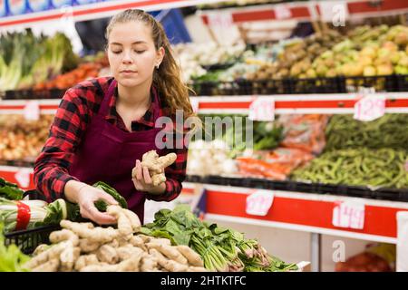 Une femme souriante a mis du gingembre sur le comptoir Banque D'Images