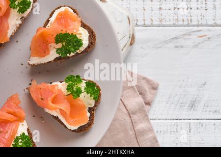 Mini sandwiches avec du saumon, du fromage caillé, du persil et du pain de seigle sous forme de coeurs.Saint-Valentin cuisine créative maison.J'adore le design du petit déjeuner.Séle Banque D'Images