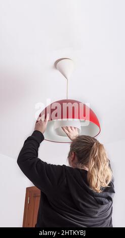 Femme blonde non reconnaissable changeant une ampoule à la maison, bricolage Banque D'Images