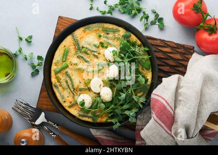 Omelette aux épinards, haricots verts, pommes de terre et épinards aliments sains dans une poêle noire sur fond rustique vieux de pierre grise. Frittata traditionnelle pour br Banque D'Images