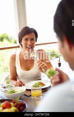 Bonne nourriture, bonne humeur. Prise de vue d'une femme attirante déjeuner avec une personne méconnaissable. Banque D'Images